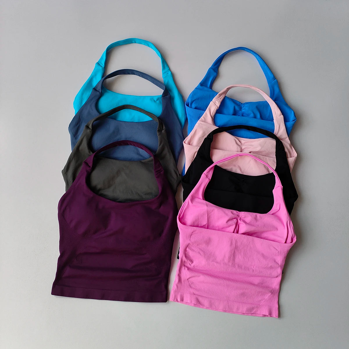 Collection de cinq hauts sans coutures à col halter pour femmes dans diverses nuances de bleu, rose et violet, disposés sur u