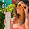 A woman holds an Owala insulated tumbler with a straw lid outdoors.