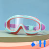 A pair of pink and teal swimming goggles resting on a light green surface.
