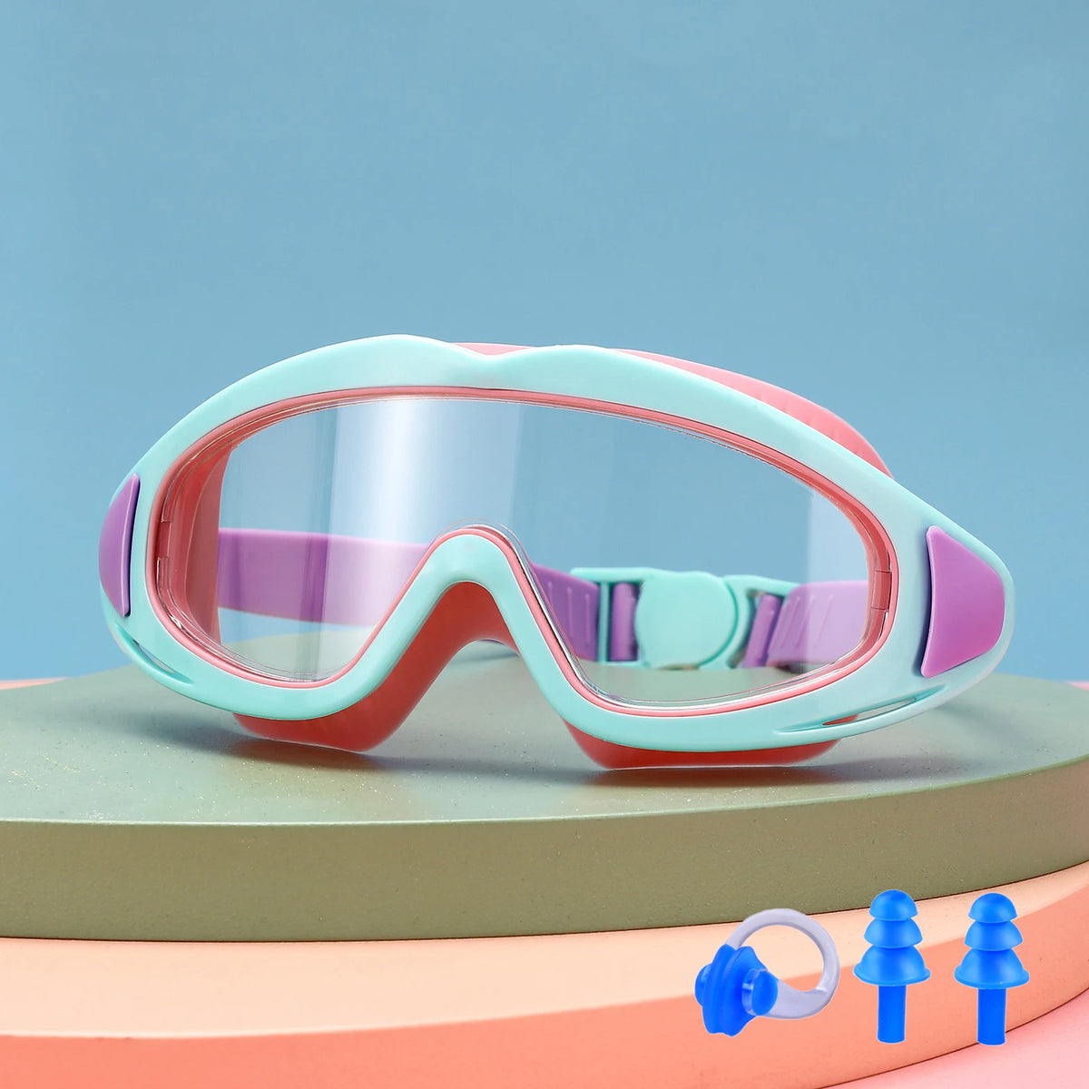 A pair of pink and teal swimming goggles resting on a light green surface.