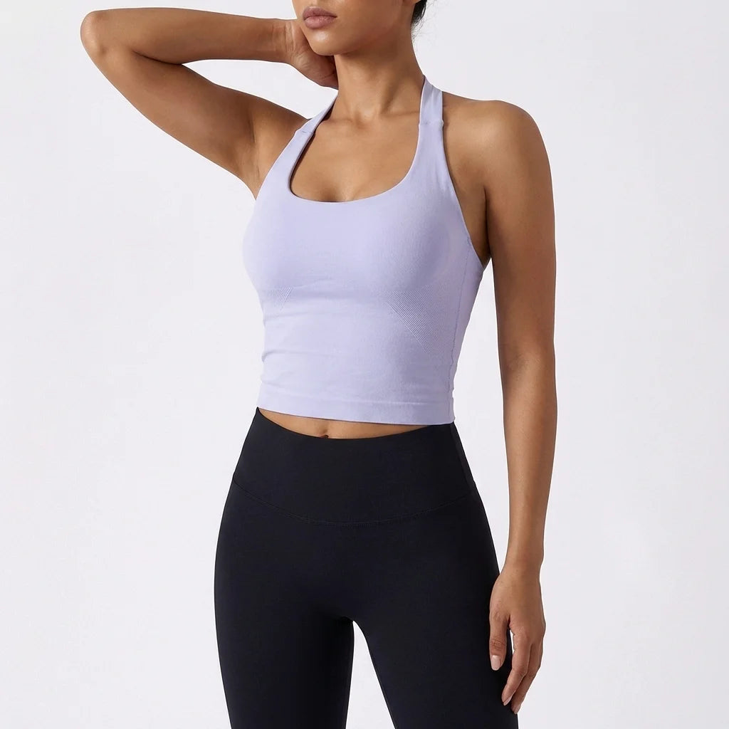 A model wearing a light purple seamless yoga and pilates sports bra and black leggings.