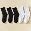 Une rangée de chaussettes en coton mélangé noires et blanches pour hommes sur un fond clair.
