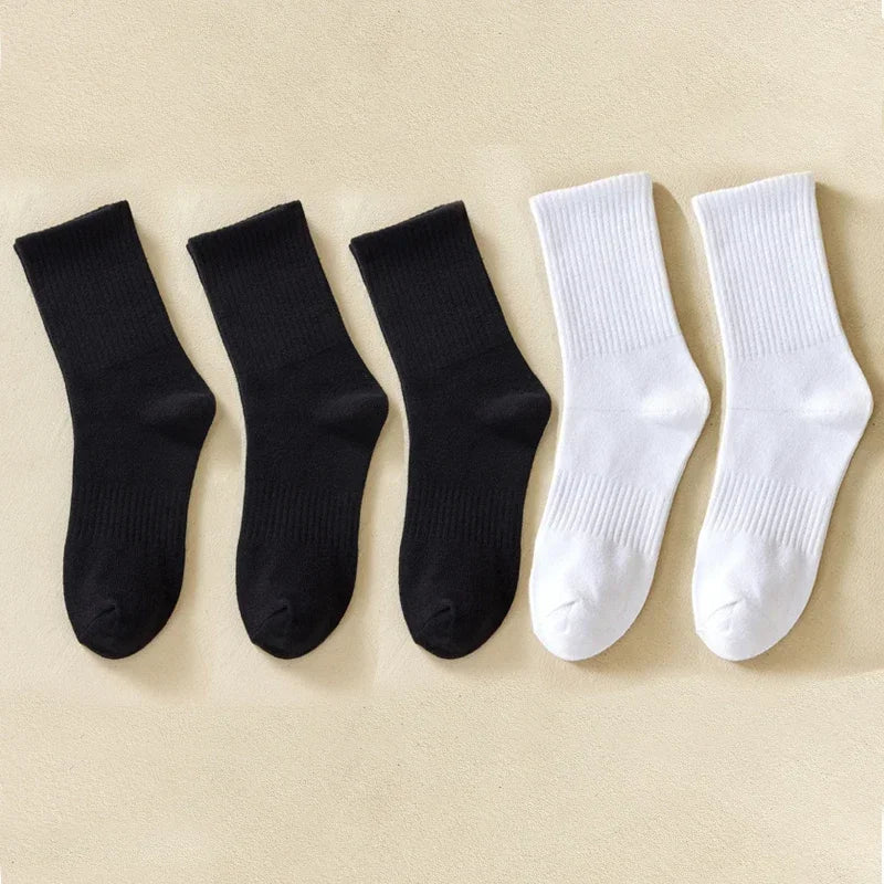 Une rangée de chaussettes en coton mélangé noires et blanches pour hommes sur un fond clair.