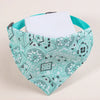 A teal patterned fabric pet scarf with a white card tucked inside, shown against a light background.