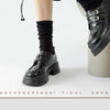 Black leather ankle boots paired with black socks shown in a studio shot.