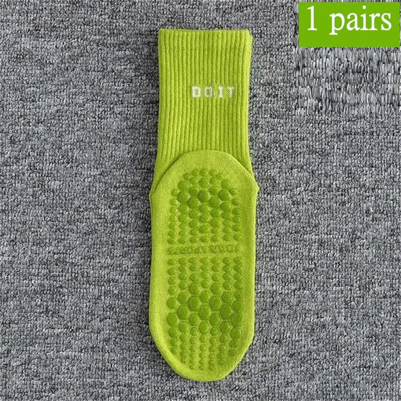 Ein Paar leuchtend limettengrüner, atmungsaktiver rutschfester Yoga- und Fitnesssocken auf einer grauen, strukturierten Oberf
