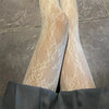 Pair of sheer floral rattan fishnet hosiery worn under dark trousers.