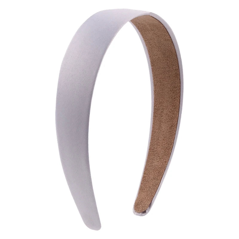A white satin hair band with a brown suede accent shown from the side.