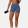 A woman wearing a navy blue high-support sports bra and matching shorts, holding a drink and a phone.