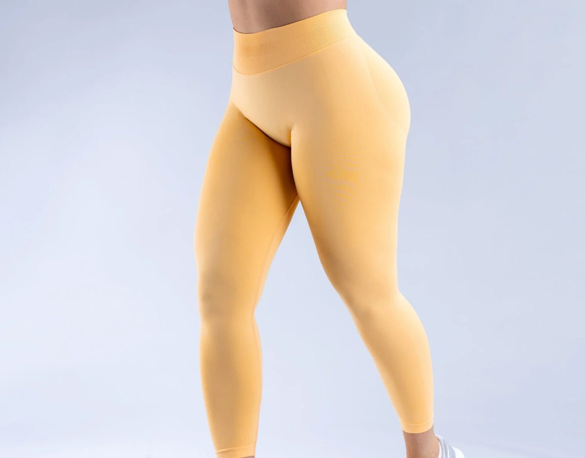 Primer plano de leggings de yoga sin costuras de cintura alta color amarillo mostaza usados por una persona.