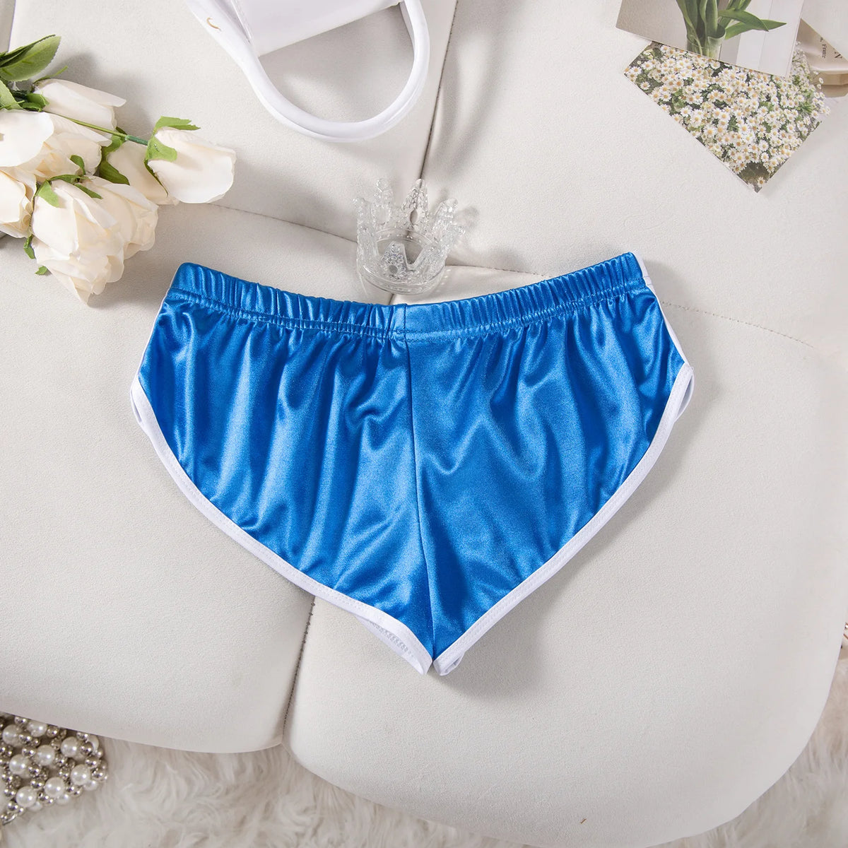 Helle blaue Satin-Sportshorts für Damen mit elastischer Taille, flach auf weißer Fläche.