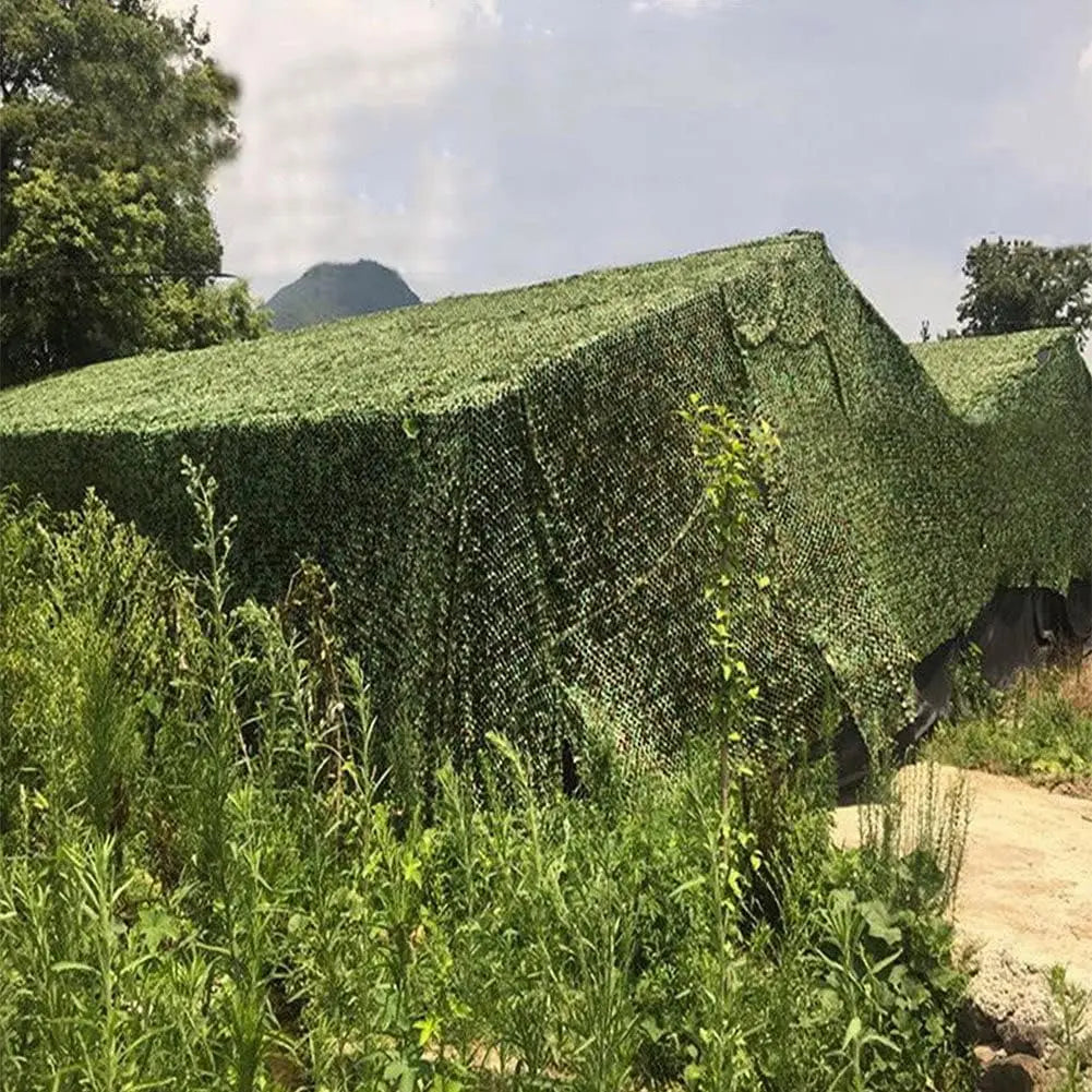 A dense green camouflage shade net covering a structure in an outdoor agricultural setting.