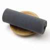 A roll of dark gray elastic bands lying next to a wooden spool.