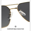 A close-up view of gold-framed sunglasses with clear nose pads and dark lenses.