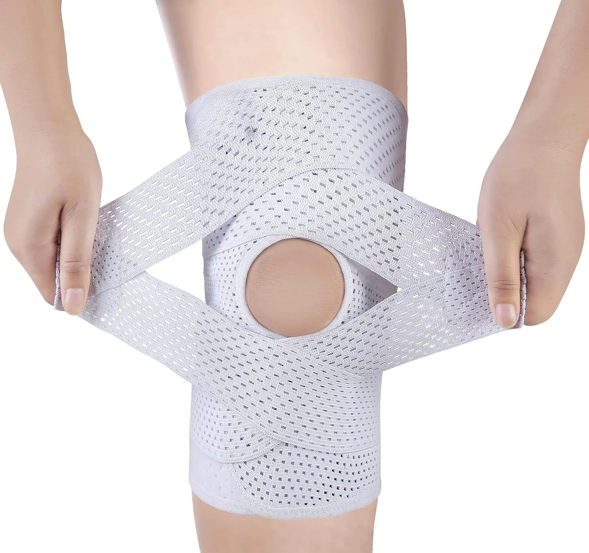 A person is holding a white adjustable knee brace with compression support, demonstrating its design.