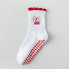 Chaussettes de yoga blanches avec broderie rouge et motif antidérapant sur la semelle.