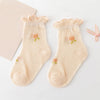 A pair of light peach baby socks with small floral embroidery are displayed on a white background.