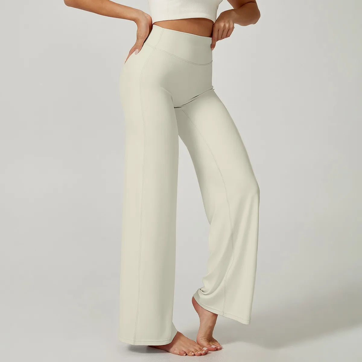 A model is wearing high waisted beige yoga pants and a white crop top.