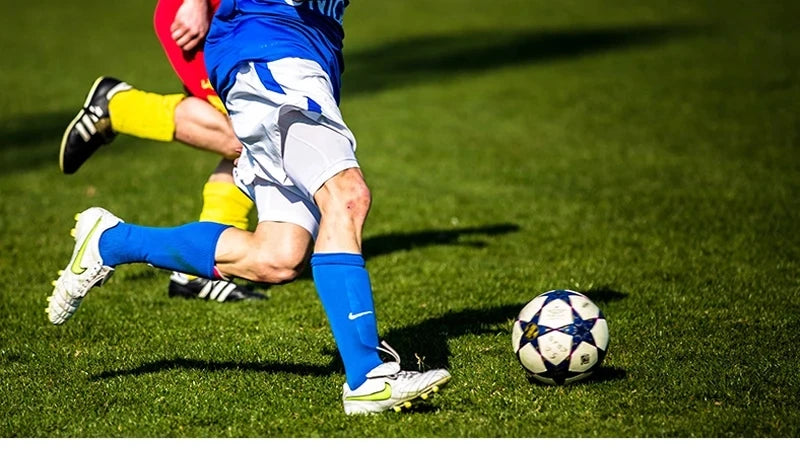 Un joueur de football en uniforme bleu et blanc frappe un ballon noir et blanc sur un terrain vert.