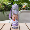 A purple cartoon drinking water bottle with a straw featuring a sleepy bear design, placed on a wooden surface.