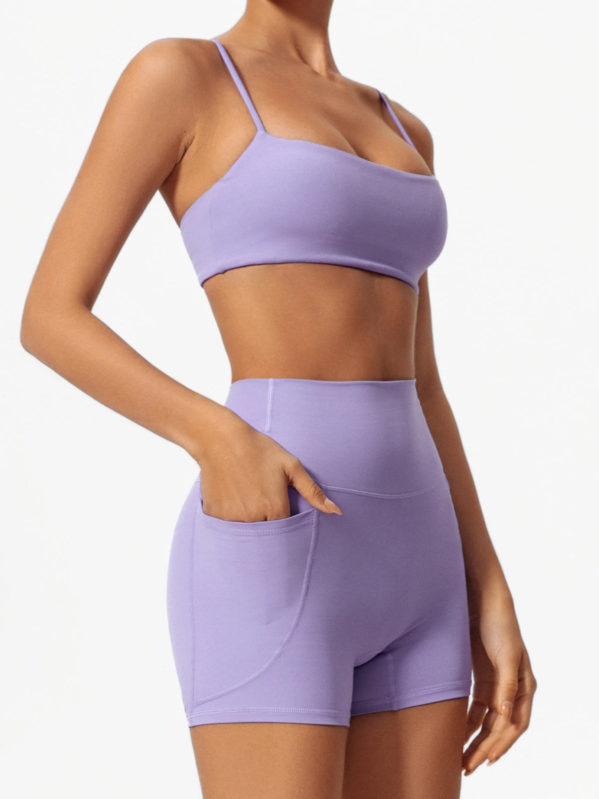 A woman wearing a lavender high-waist yoga and workout set consisting of a cropped top and matching shorts.