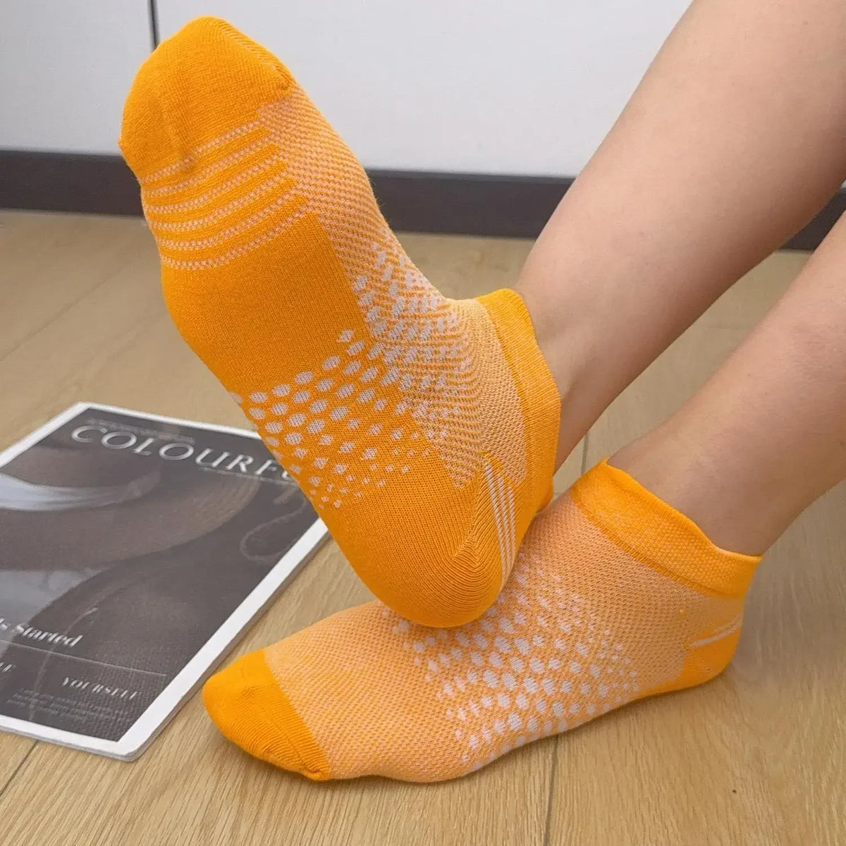 A pair of bright orange breathable mesh ankle socks worn on a person's foot.