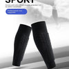 Black elastic sports shin guards shown in a close-up view against a blurred outdoor sport background.