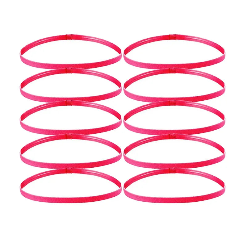 A set of five bright pink elastic sports headbands laid out in a row.