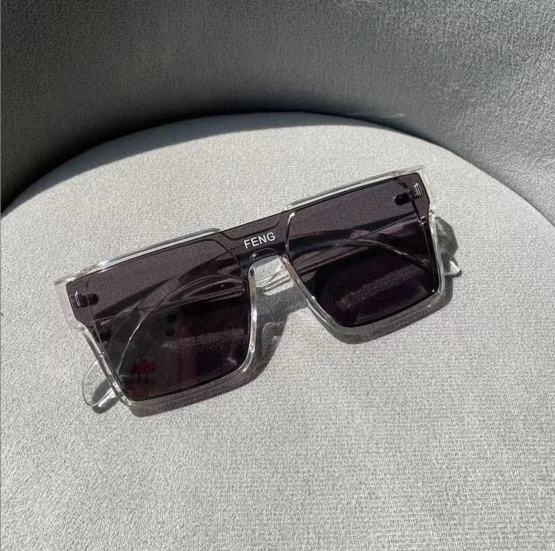 A pair of dark purple tinted square sunglasses with a thin silver frame resting on a light gray surface.
