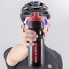 A person holds a black sports water bottle with red accents against a light gray background.