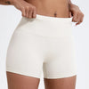 Gros plan d'une femme portant des shorts de yoga et de sport à taille haute et compressifs de couleur beige clair.