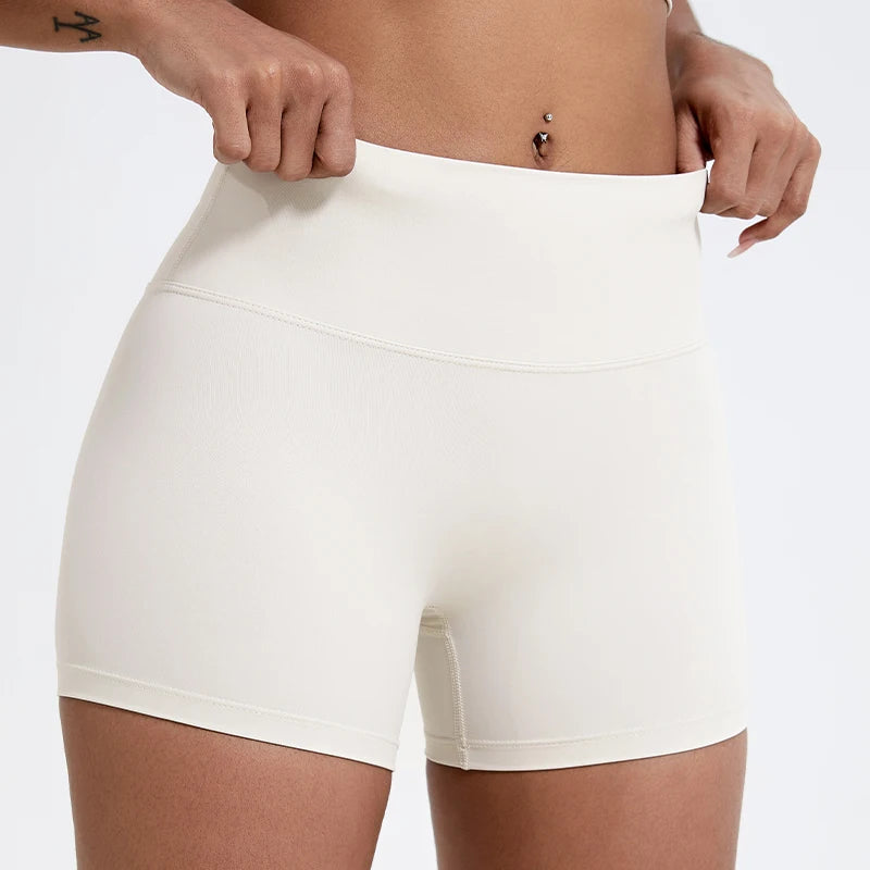 Gros plan d'une femme portant des shorts de yoga et de sport à taille haute et compressifs de couleur beige clair.