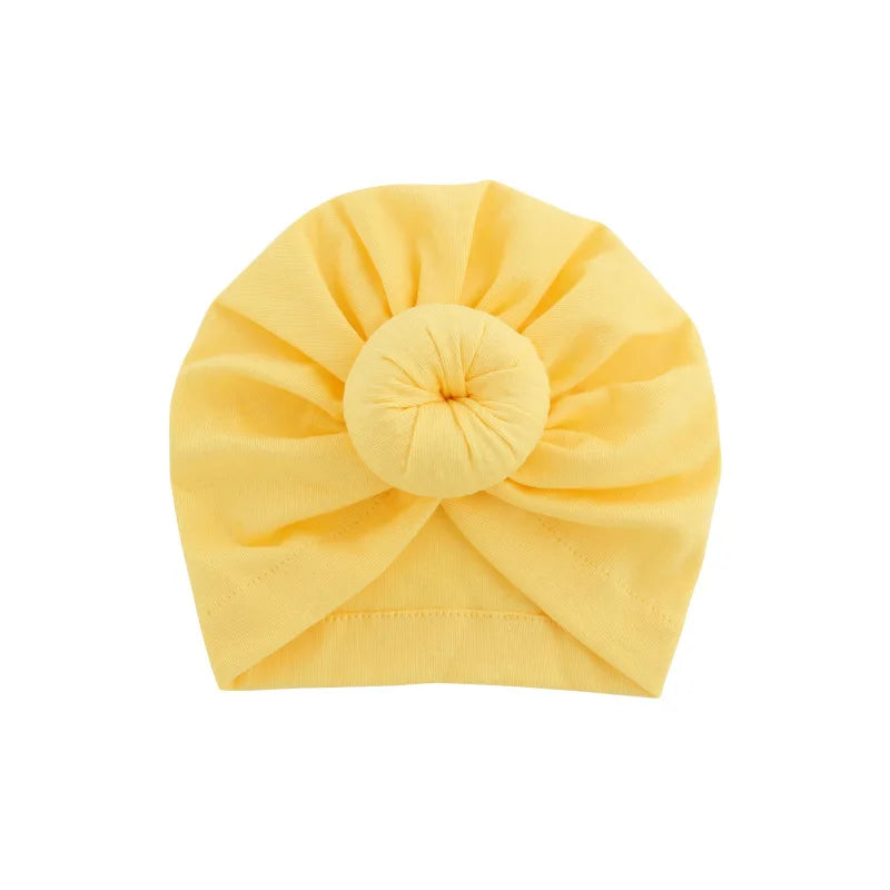 Gelbes, solides Baumwoll-Baby-Turban, gefaltet in eine Rosettenform.