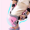 A close-up of a child's leg wearing pink and gray protective gear including knee pads and wrist guards for skating.