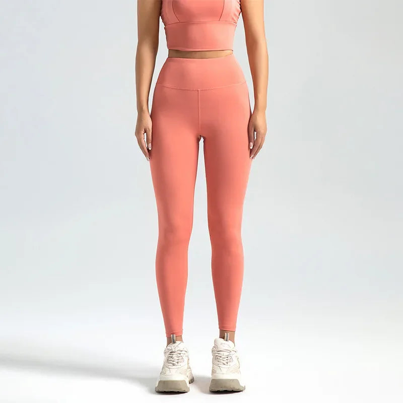A model wearing seamless high-waist yoga leggings in a coral pink color.