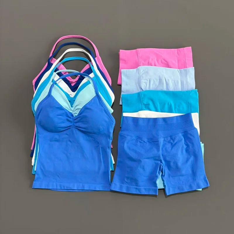 A stack of women's seamless backless fitness set tops and shorts in various shades of blue, pink, and white.