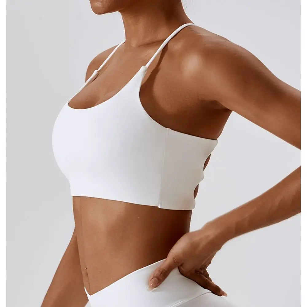 Primer plano de un sujetador deportivo en forma de U blanco usado por una modelo, mostrando el ajuste y el diseño.