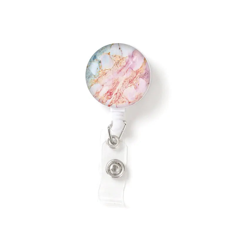 A round, marbled pendant featuring pink and blue tones attached to a clear keychain.