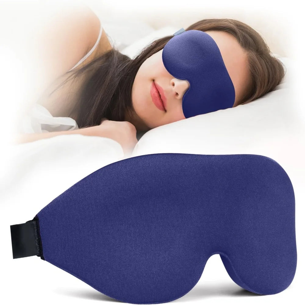 A dark blue light blocking sleep mask is shown being worn by a woman resting on a pillow.