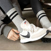 A close-up of a person's foot wearing Nike sneakers and striped athletic socks.