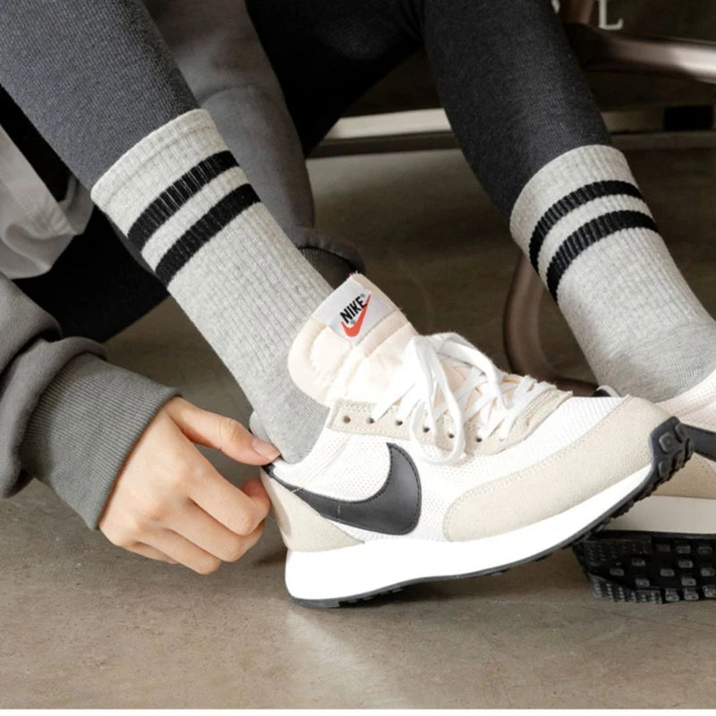 A close-up of a person's foot wearing Nike sneakers and striped athletic socks.