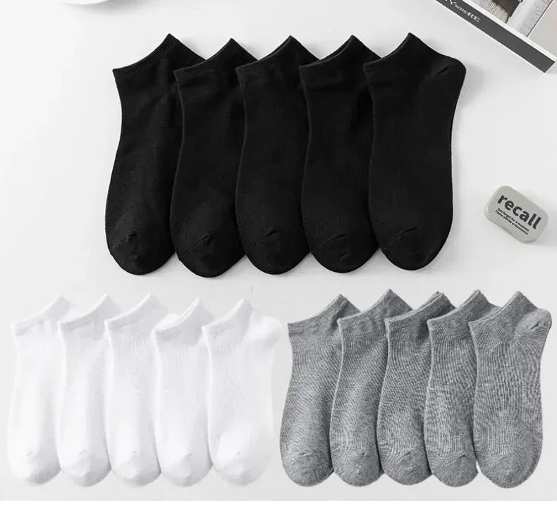 Eine Sammlung von schwarz-grauen Knöchelsocken auf einer weißen Oberfläche.