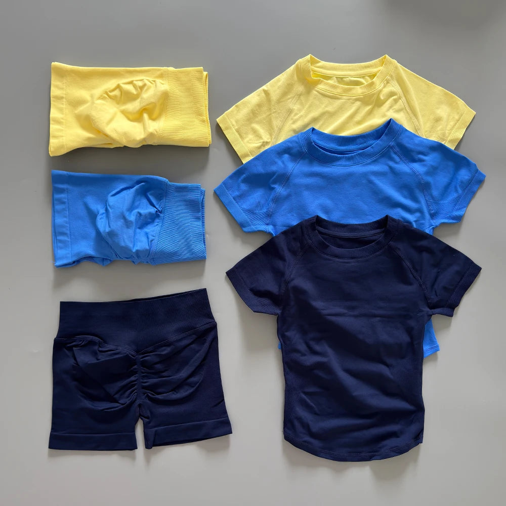 Un ensemble de vêtements de sport et de yoga sans couture, comprenant un haut jaune, un haut bleu et un short marine.