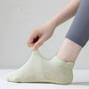 A hand is putting on a light green mesh yoga and fitness sock on a person's foot.