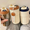 A set of ceramic thermo mugs with gold accents and LED temperature displays sitting on a gray fabric.