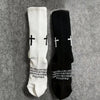 Pair of white and black cross printed athletic socks displayed on a gray background.