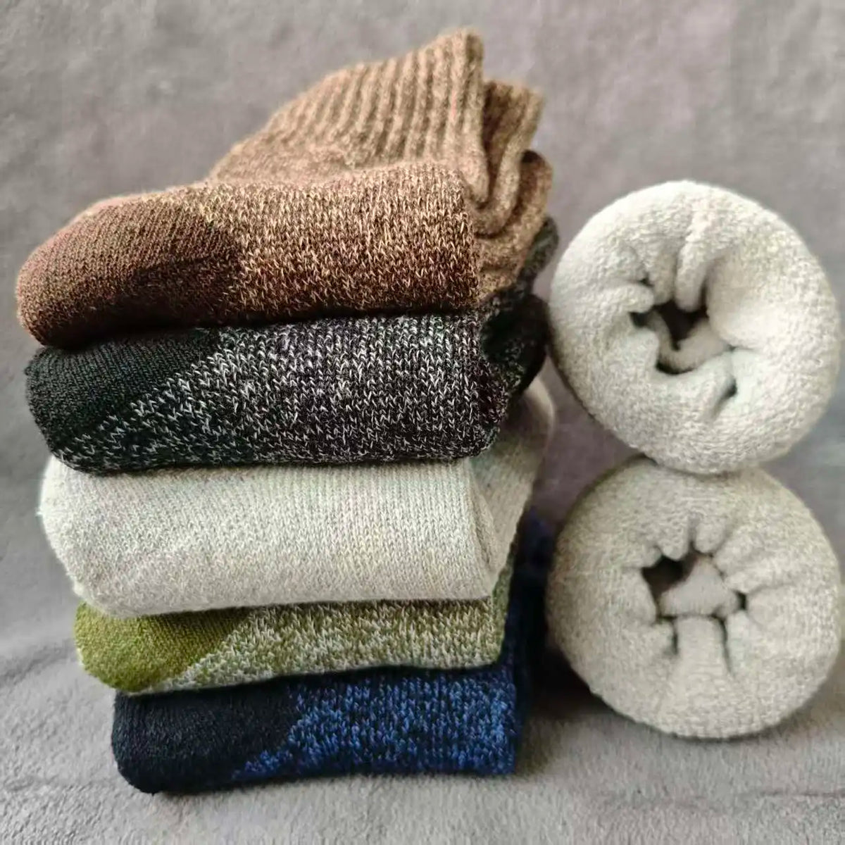 A stack of three brown, black, and beige merino wool hiking socks