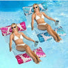 A smiling woman wearing a white bikini is relaxing on an inflatable pool float hammock in clear blue water.