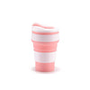 A pink and white reusable silicone collapsible coffee cup with a lid.