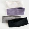 Un paquete de cuatro bandas elásticas para el cabello en blanco, morado, gris y negro.